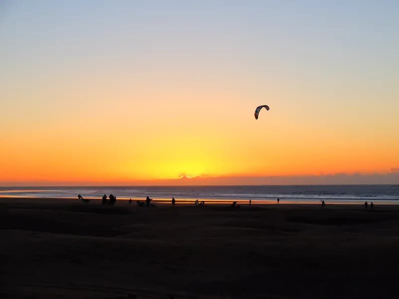 Aile de kitesurf devant le soleil couchant sur la plage d’Essaouira