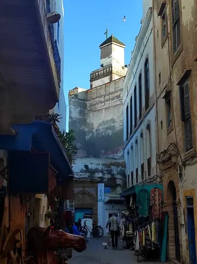 Ruelle blanche et bleue de la médina d’Essaouira menant à une tour fortifiée