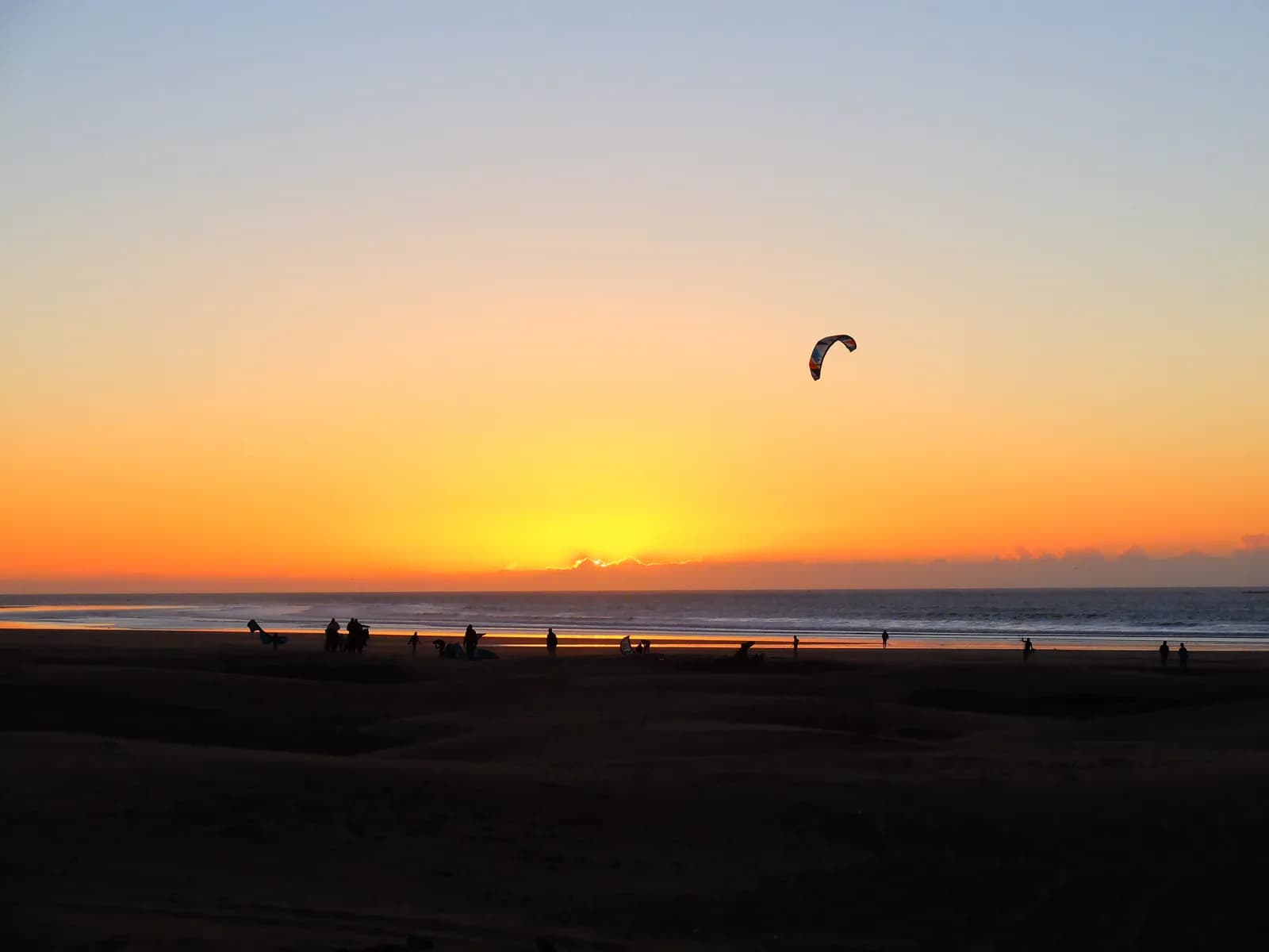 Aile de kitesurf devant le soleil couchant sur la plage d’Essaouira