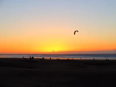 Aile de kitesurf devant le soleil couchant sur la plage d’Essaouira